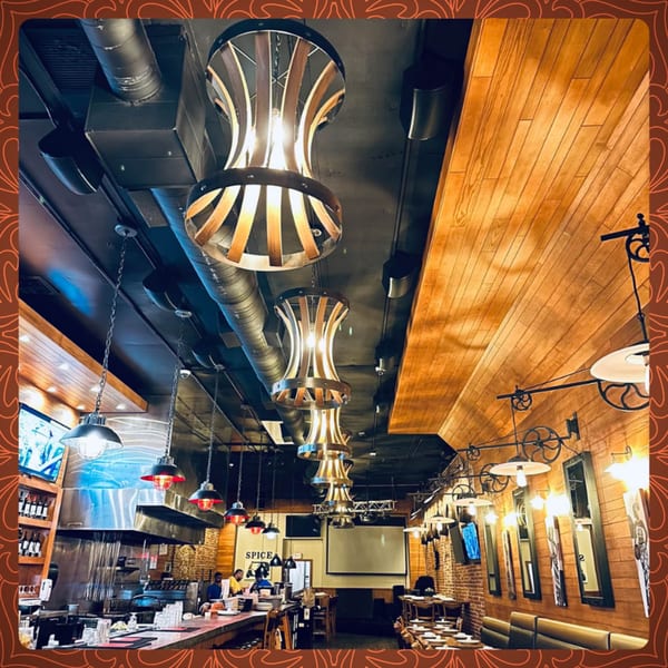 Interior of Spice Social restaurant with warm lighting, exposed brick, wooden accents, and a bar area.